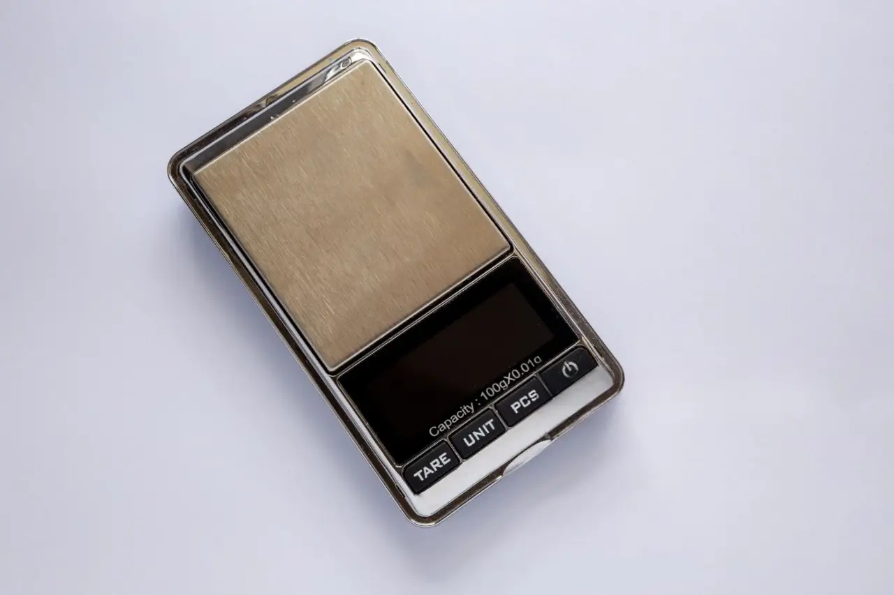 Digital pocket scale. Display shows capacity: 100g x 0.01g, with buttons for 'Tare', 'Unit' and 'Pieces'
