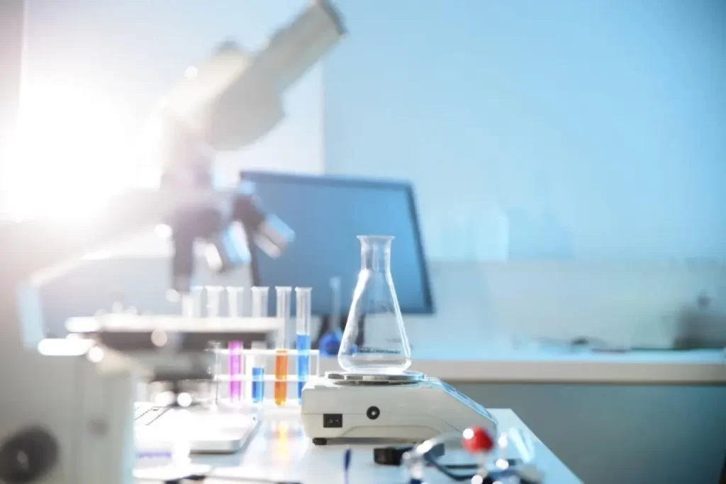 A science lab bench with an Erlenmeyer flask on a digital scale, surrounded by various lab equipment.
