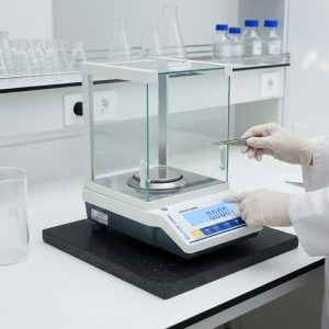 Stuccler precision electronic analytical balance on a vibration-dampening stone in a professional laboratory setting.