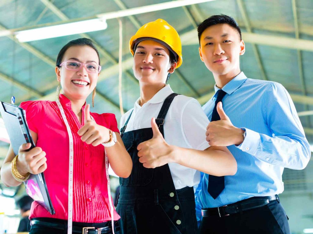 Three professional staff members - a businesswoman, a factory worker, and a manager - giving thumbs up with smiles.