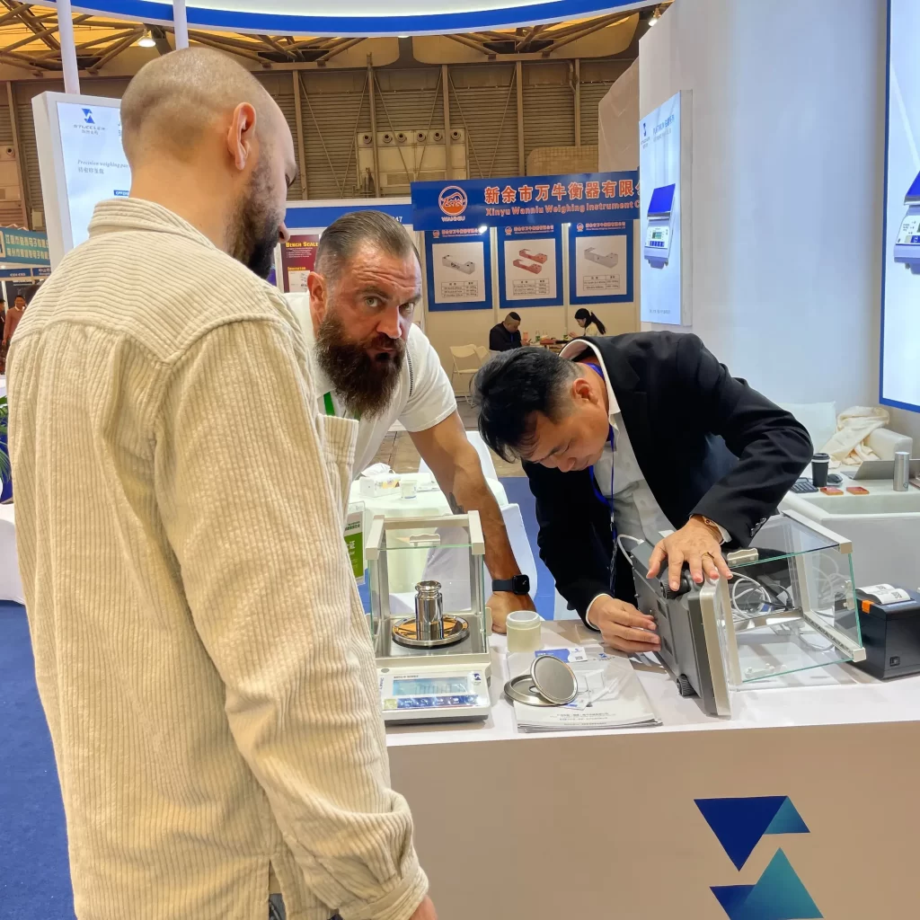 Stuccler engineer demonstrating analytical balance operation to client.