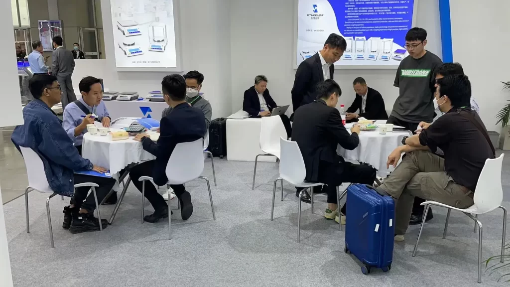 International clients discussing Stuccler precision scales at trade show.